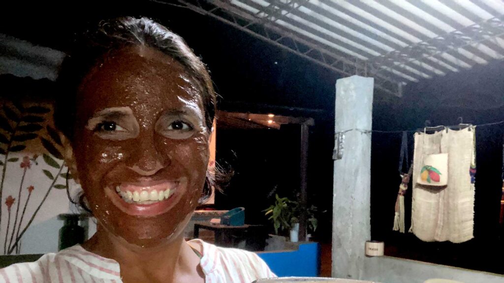 Paola Yepes smiling with her face covered in a glistening chocolate or cacao facial mask at a Cacao Farm in Paso del Mango, Bonda, Colombia.