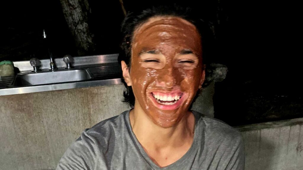 Person smiling with their face covered in a chocolate or cacao facial wrap at a Cacao Farm in Paso del Mango, Bonda, Colombia.