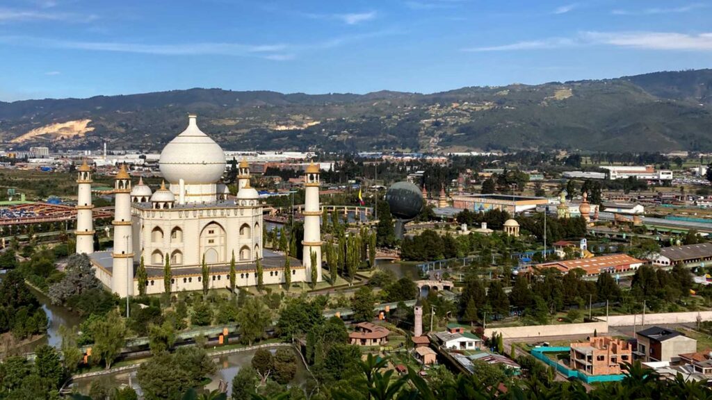 A large replica of the Taj Mahal in Parque Jaime Duque, Bogotá, Colombia, with other miniature monuments and green hills in the background.